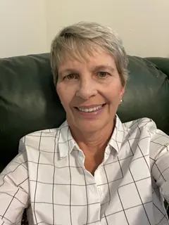 A woman sitting on top of a couch wearing a white shirt.