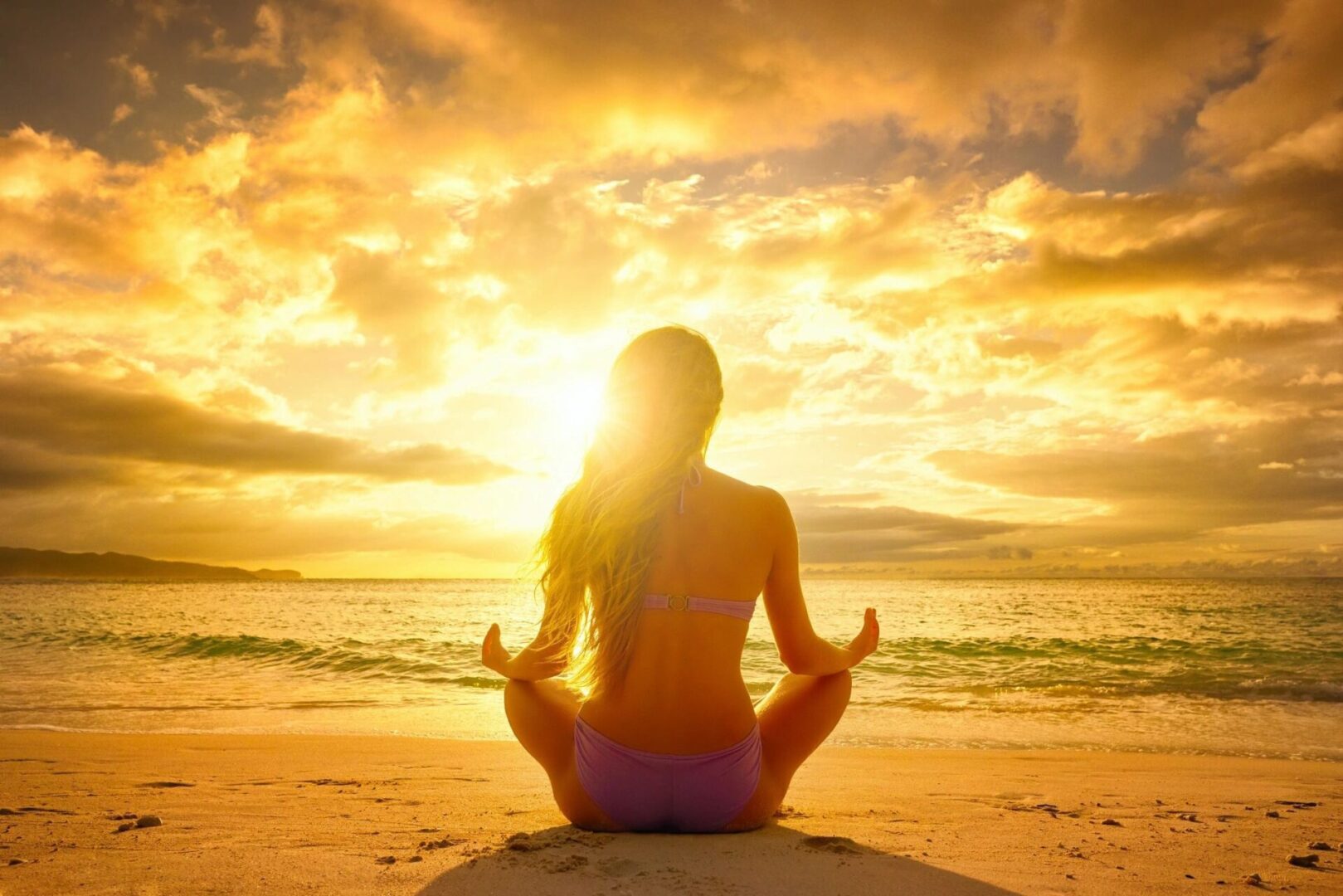 A woman sitting on the beach in front of the ocean.