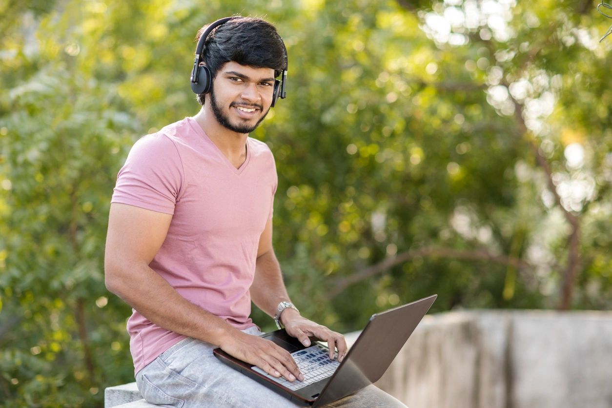 A man wearing headphones and using a laptop.